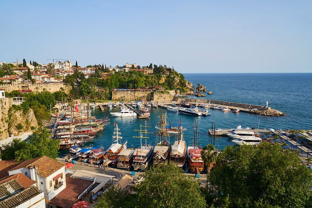 Oude haven van Antalya met houten rondvaartboten en de kliffen van de oude stad