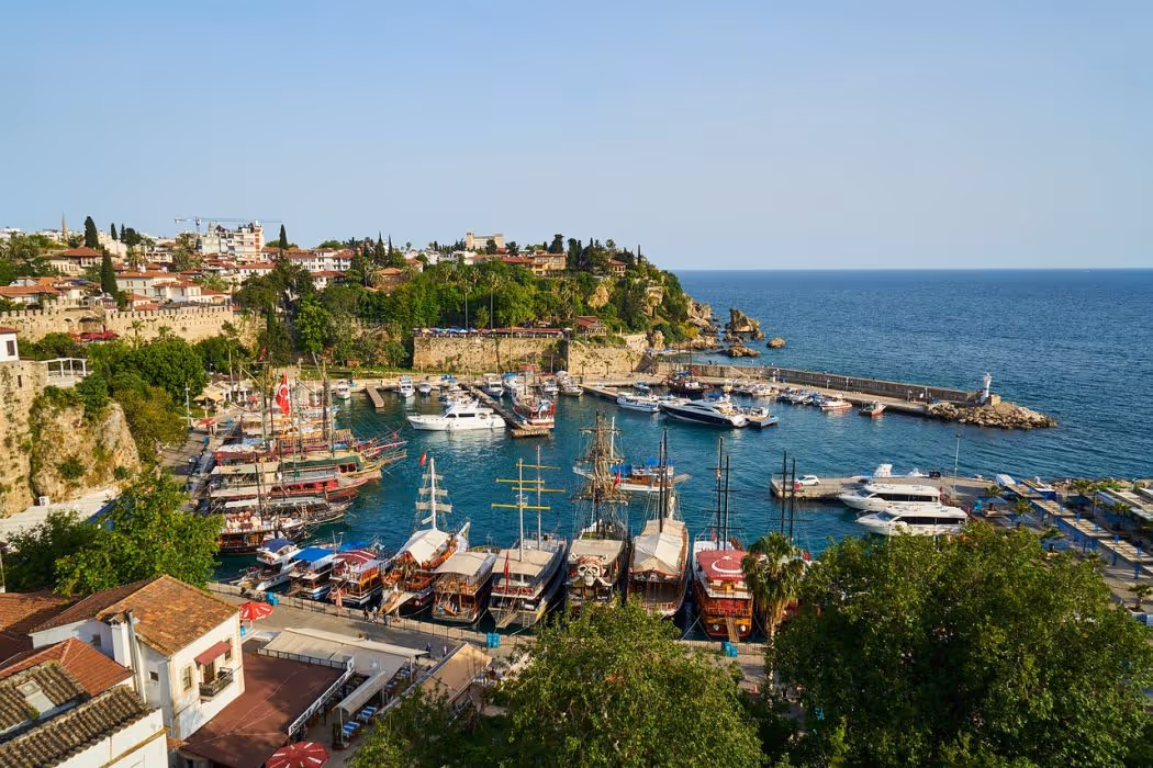 Oude haven van Antalya met houten rondvaartboten en de kliffen van de oude stad