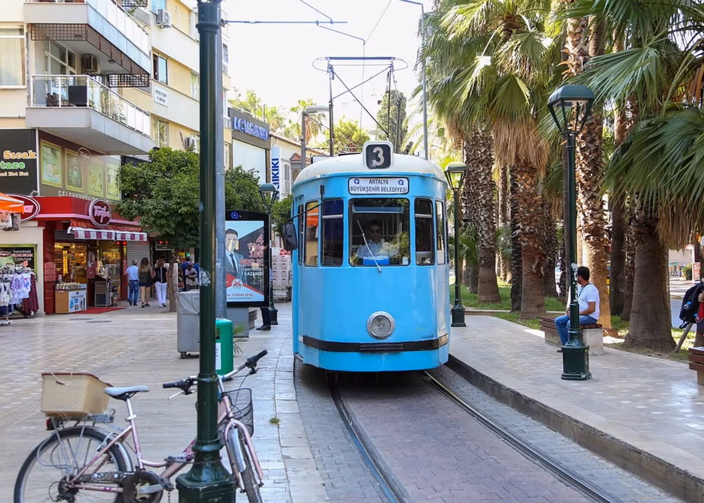 Historische trammetje dat tussen palmen door een straat in het centrum van Antalya rijdt