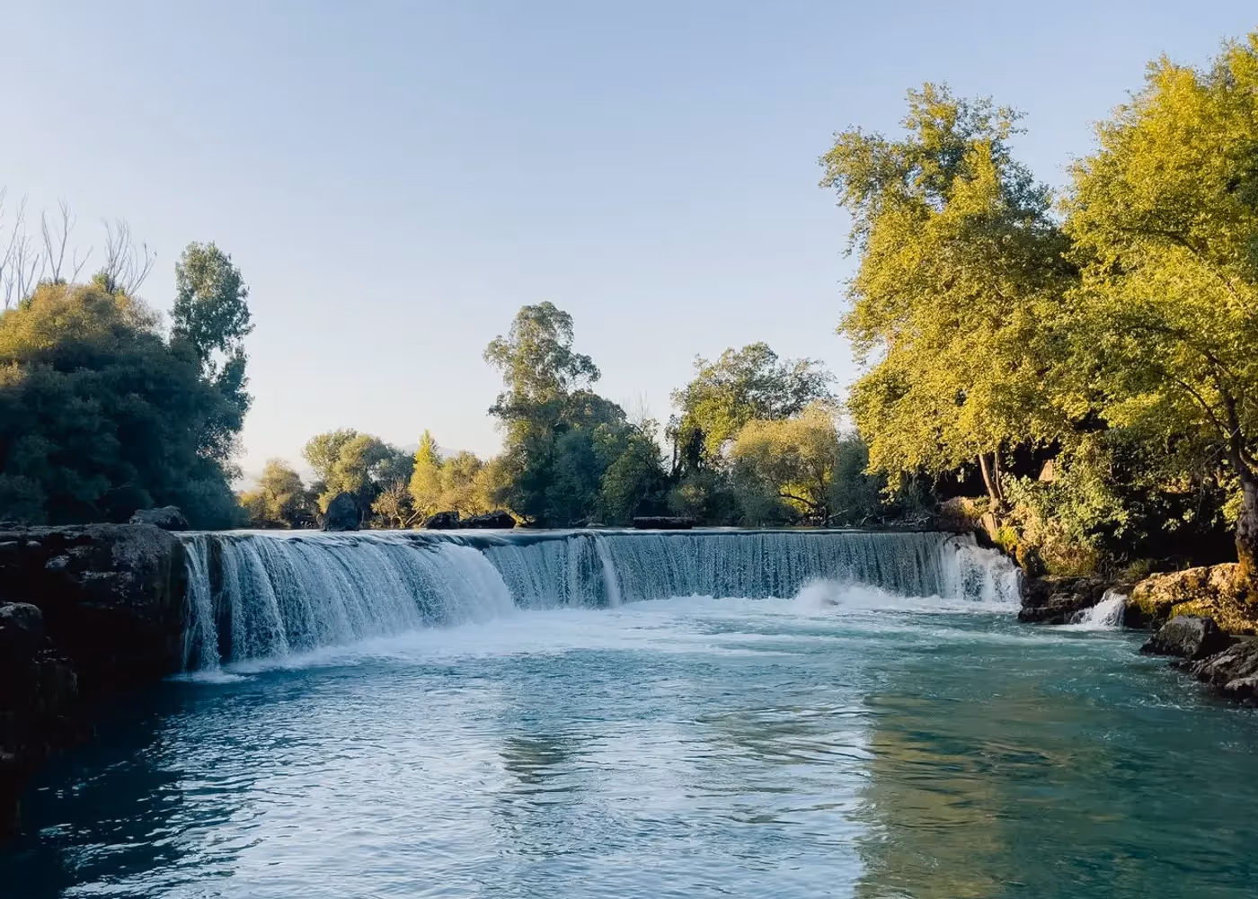 Brede waterval tussen bomen en struiken in het natuurpark Kurşunlu bij Aksu