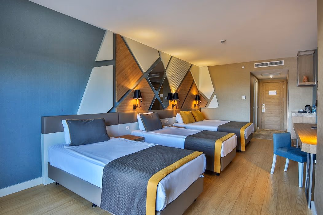 Kamer met drie bedden, blauwgrijze wanden en wandpanelen in X-vorm in Saturn Palace Resort in Lara