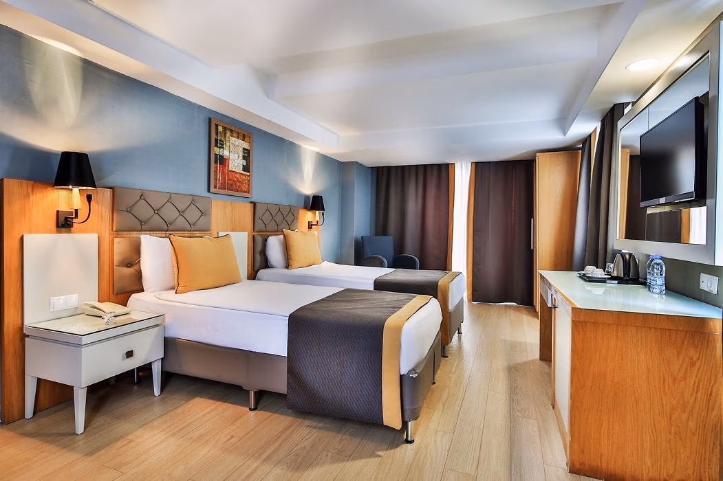 Kamer met een tweepersoonsbed, een eenpersoonsbed, een bureau en een tv in Saturn Palace Resort