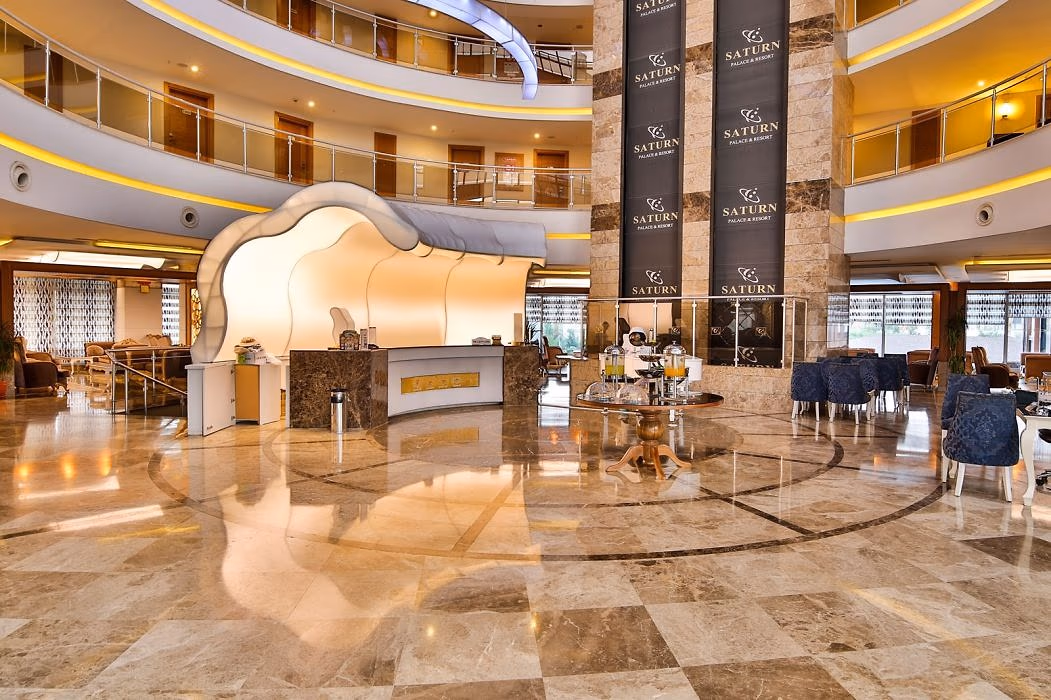 Lobby met marmeren vloer, receptiebalie en open galerijen op de verdiepingen in Saturn Palace Resort