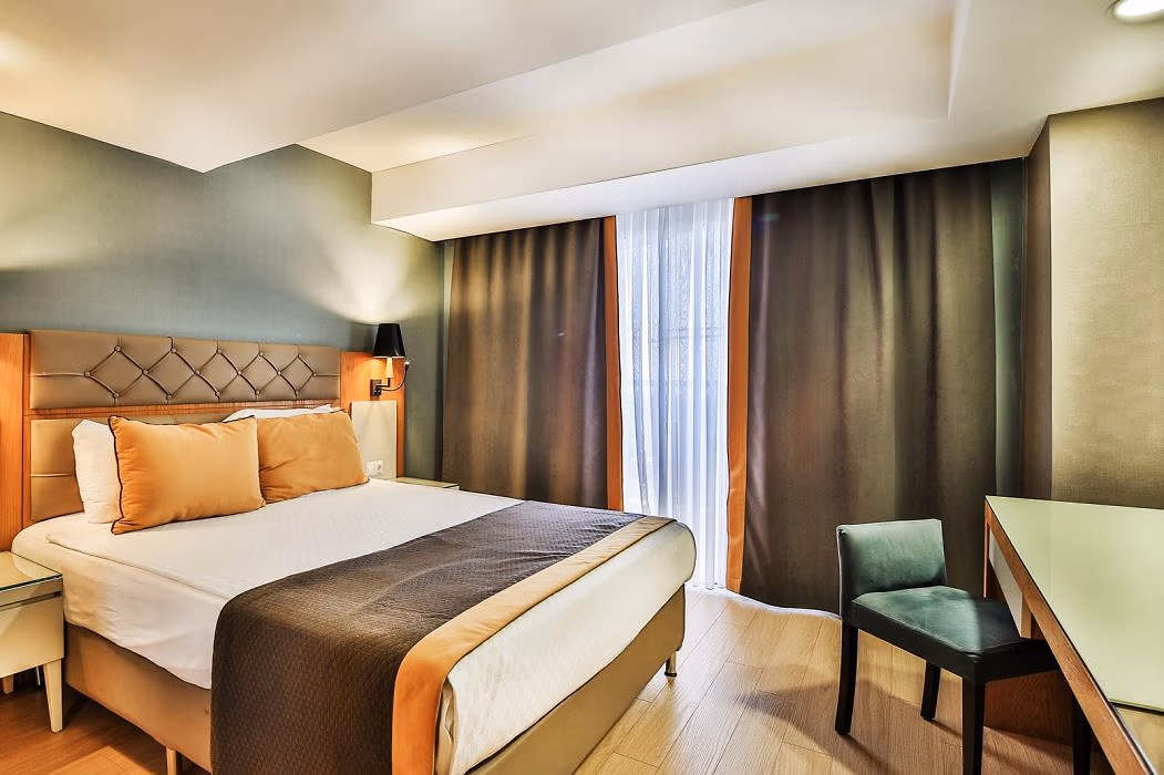 Kamer met een tweepersoonsbed, lange gordijnen en een fauteuil in Saturn Palace Resort