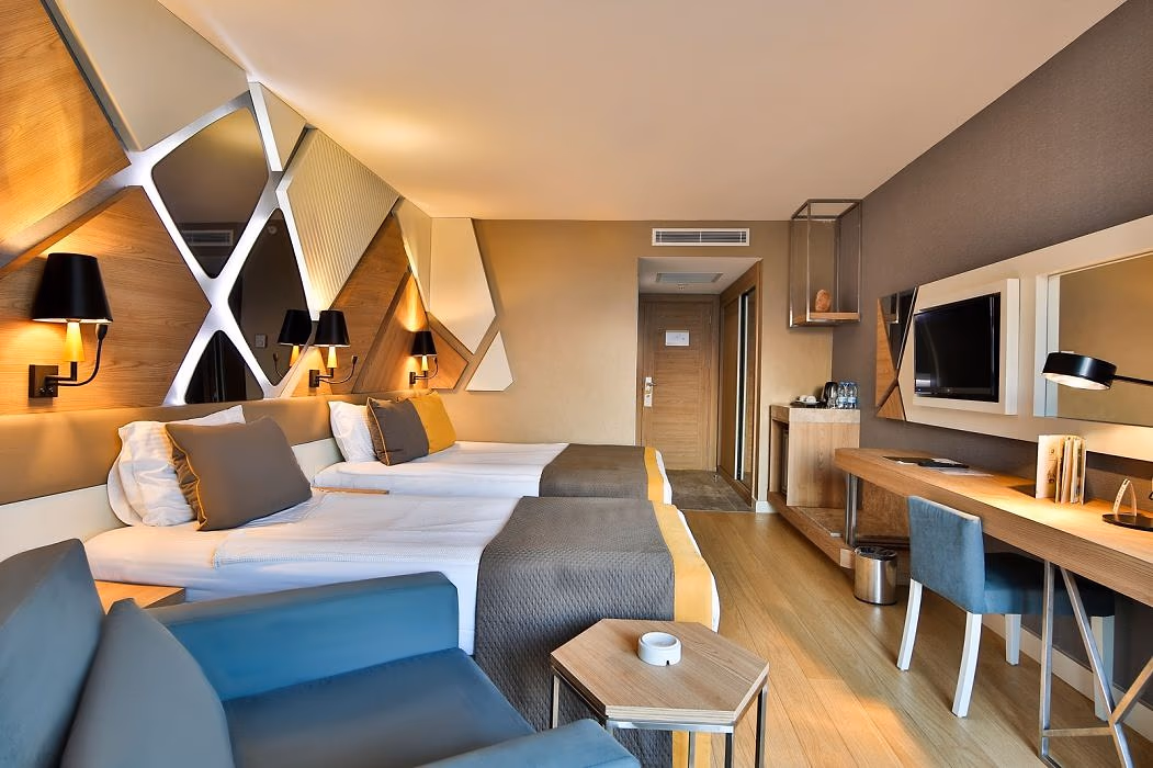 Kamer met een tweepersoonsbed en een eenpersoonsbed, wandpanelen in X-vorm en een bureau in Saturn Palace Resort in Lara