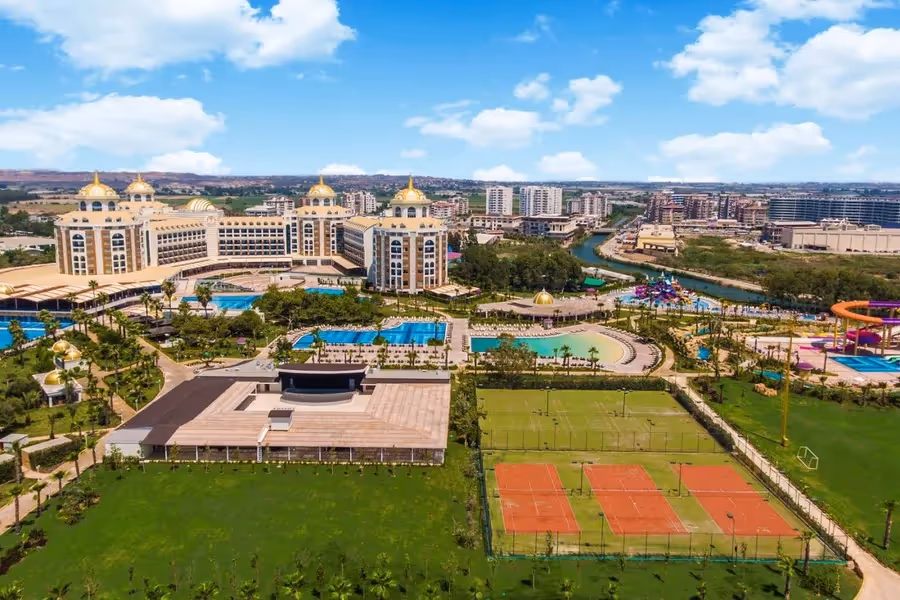 Delphin Be Grand Resort van boven, met de gebouwen met gouden koepels, de zwembaden, de tennisbanen en de rivier
