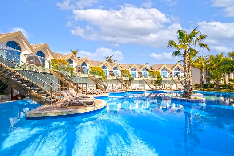 Palmbomen rond het zwembad en de villa's van Long Beach Resort in Türkler bij Alanya