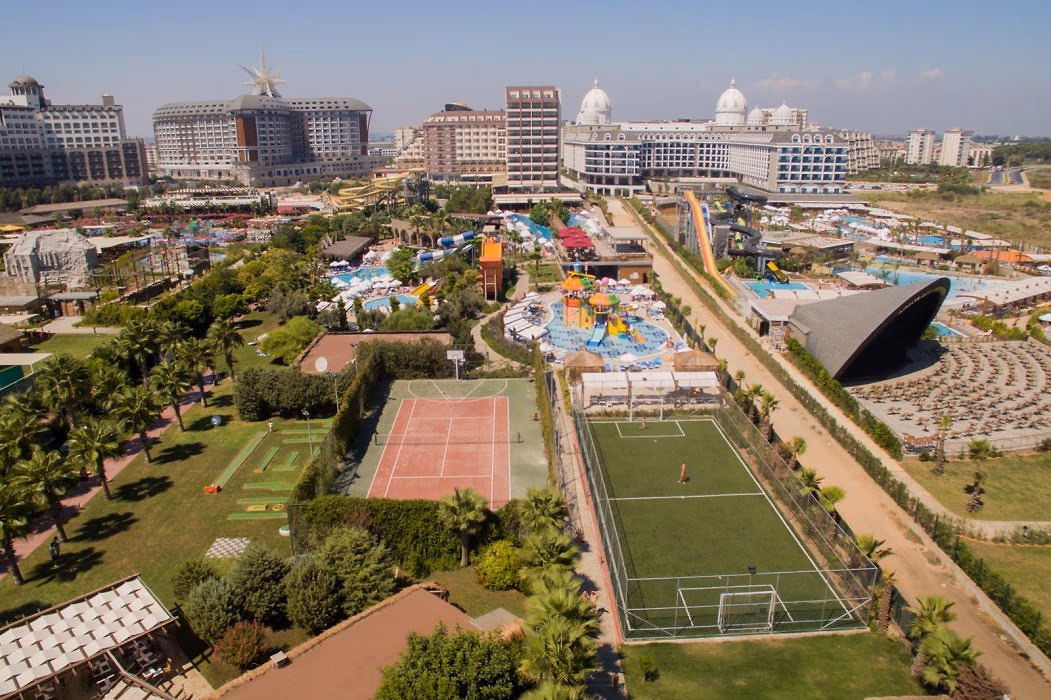 Luchtfoto van de tennisbaan en het voetbalveld met het aquapark en de buurhotels erachter bij Saturn Palace Resort