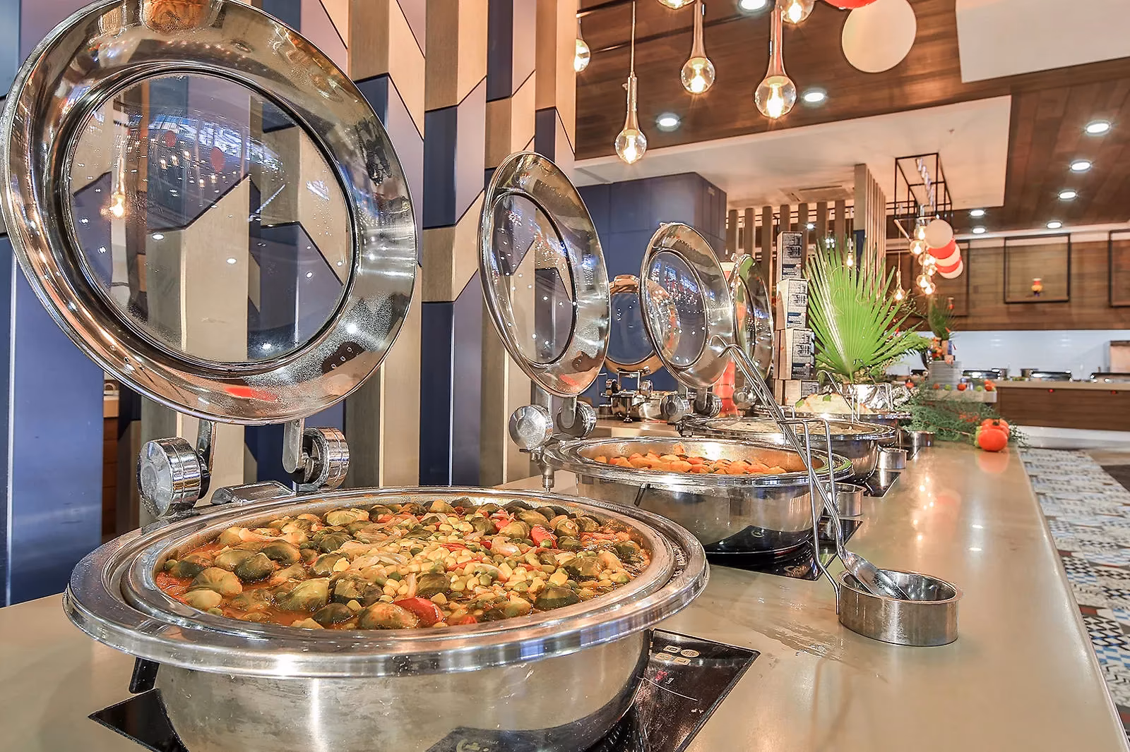 Warme gerechten in glanzende schalen met deksels aan het buffet van Saturn Palace Resort
