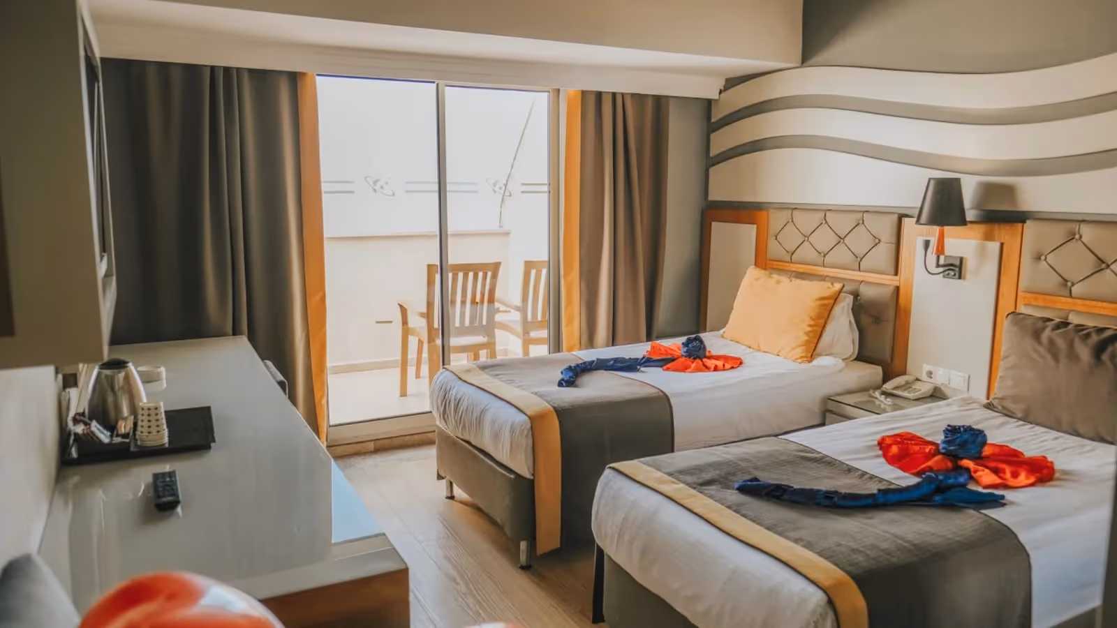 Familiekamer met twee eenpersoonsbedden met handdoekdecoratie en een schuifpui naar het balkon in Saturn Palace Resort in Lara