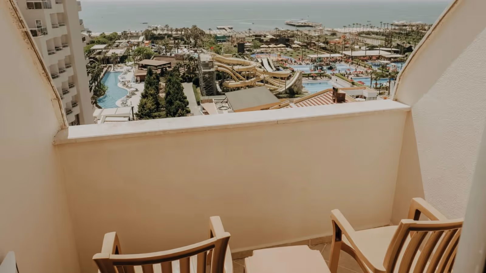 Balkon met twee stoelen en uitzicht op de zwembaden en glijbanen bij Saturn Palace Resort in Lara