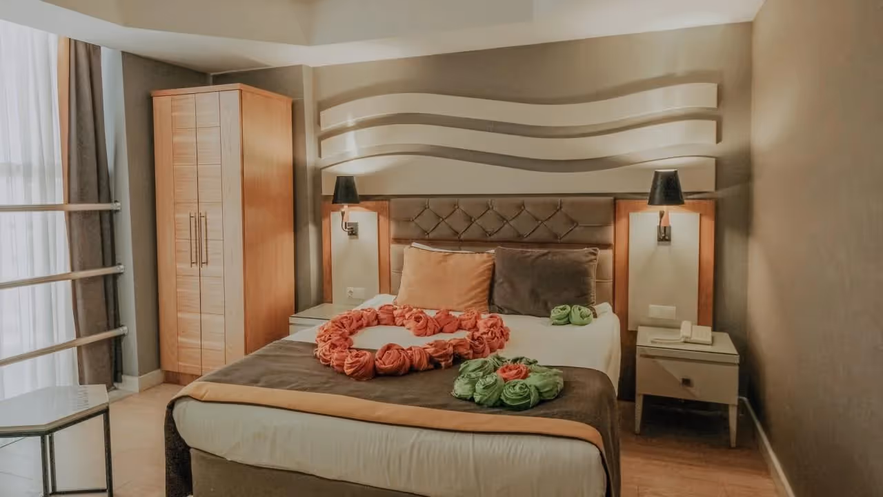 Slaapkamer met tweepersoonsbed, hoge kledingkast en nachtkastjes in Saturn Palace Resort in Lara