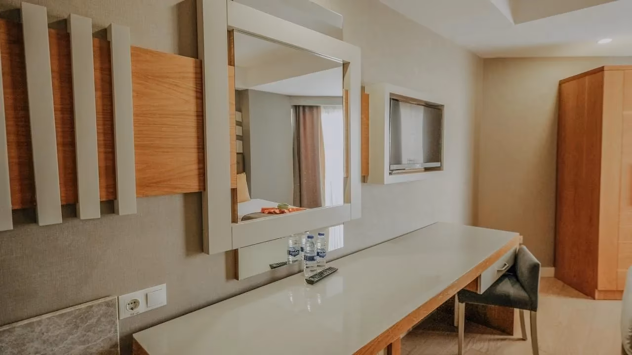 Bureau met spiegel en tv tegen een lichte wand in Saturn Palace Resort in Lara