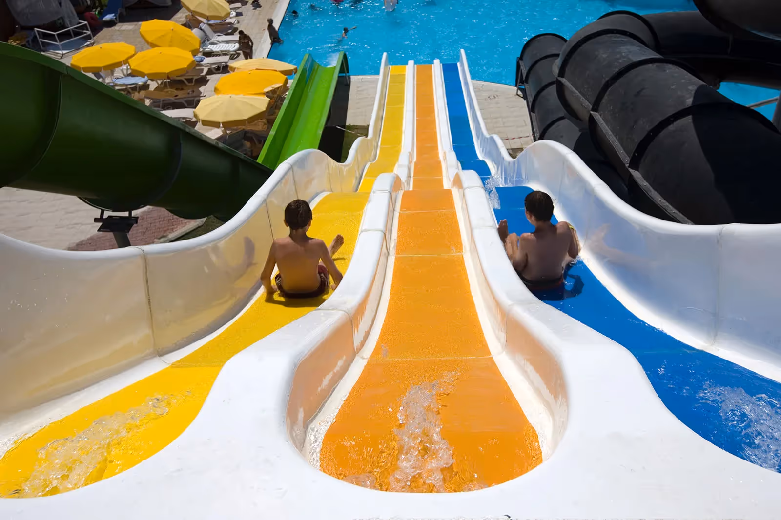 Twee kinderen op een gele en een blauwe waterglijbaan bij Saturn Palace Resort in Lara