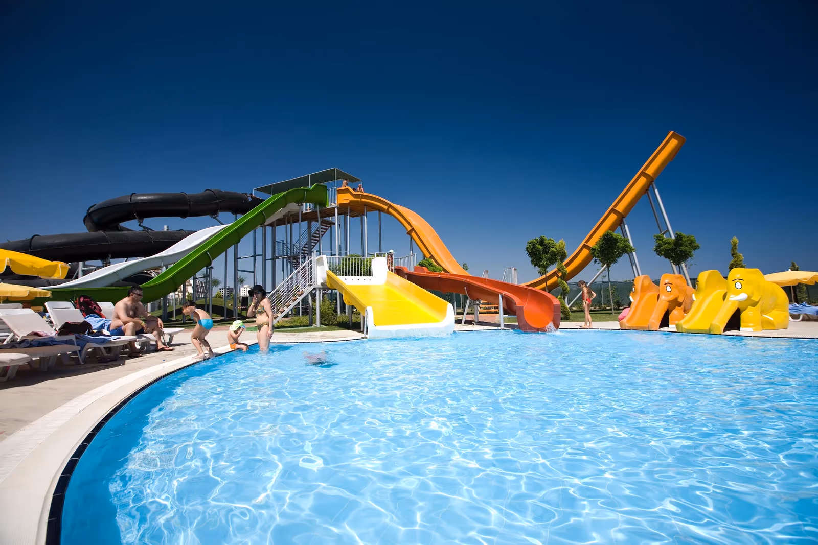 Zwembad met een rij gekleurde glijbanen en ligbedden op de rand bij Saturn Palace Resort in Lara