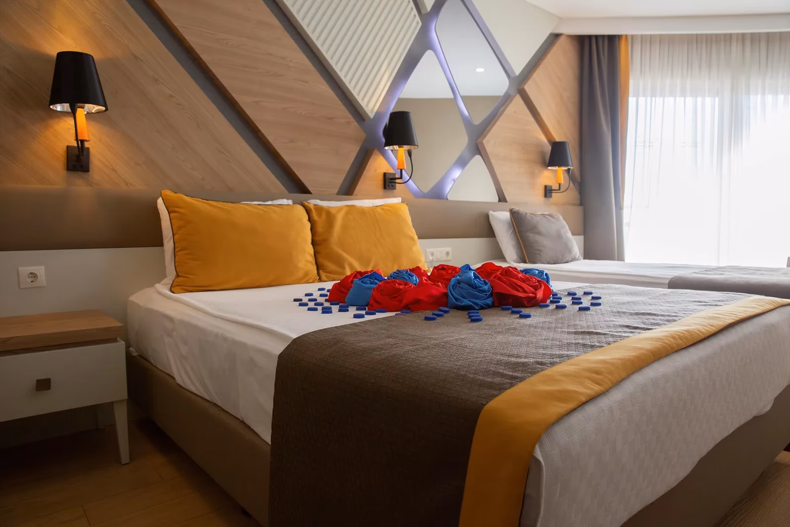 Tweepersoonsbed met decoratie onder een wand met lichtpanelen in X-vorm in Saturn Palace Resort in Lara