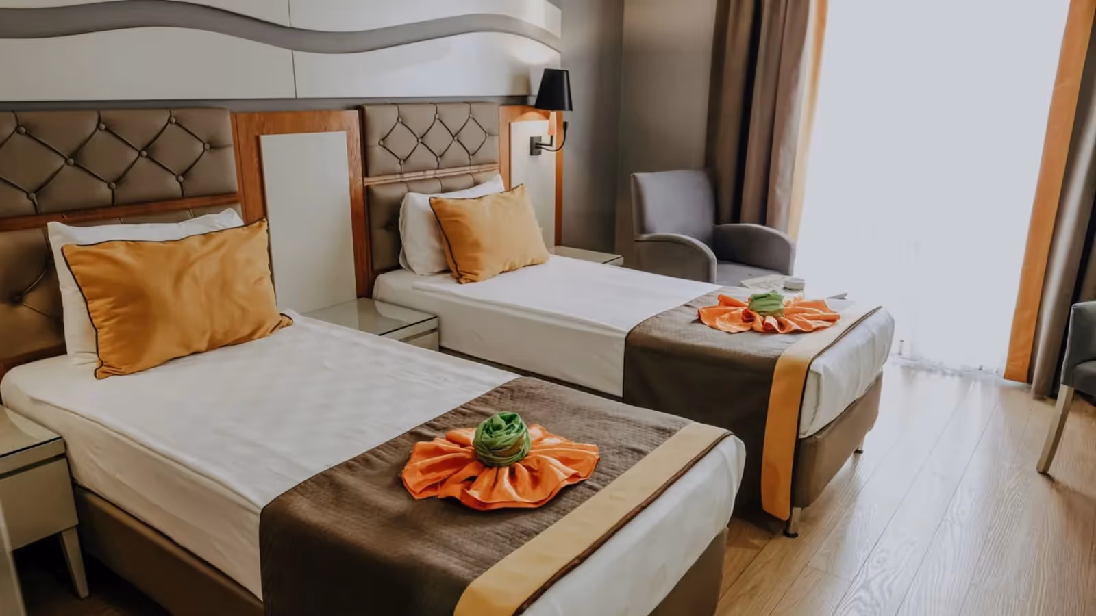 Standaardkamer met landzicht in Saturn Palace Resort met twee eenpersoonsbedden met oranje kussens en een fauteuil bij het raam