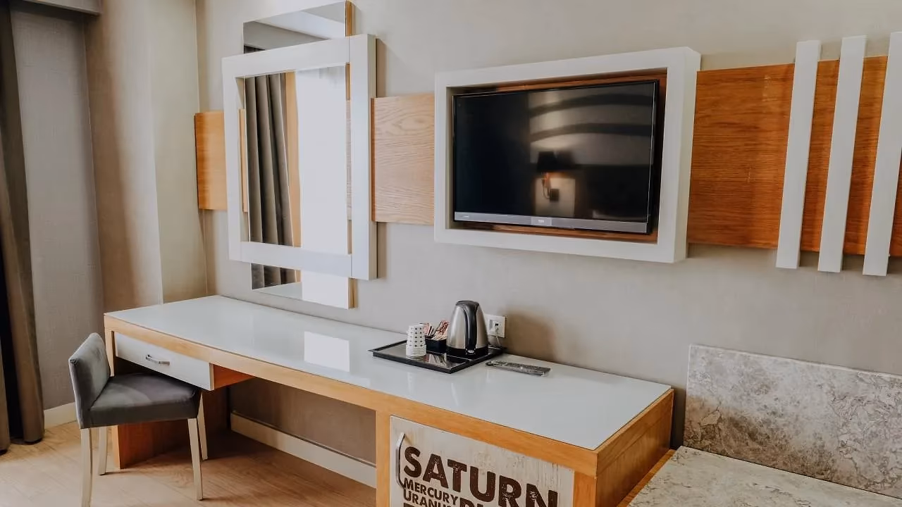 Bureau met waterkoker, spiegel en een tv aan de wand in een standaardkamer met landzicht van Saturn Palace Resort