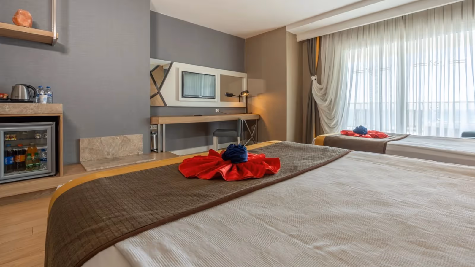 Opgemaakt bed met handdoekdecoratie en een bureau met tv in Saturn Palace Resort in Lara