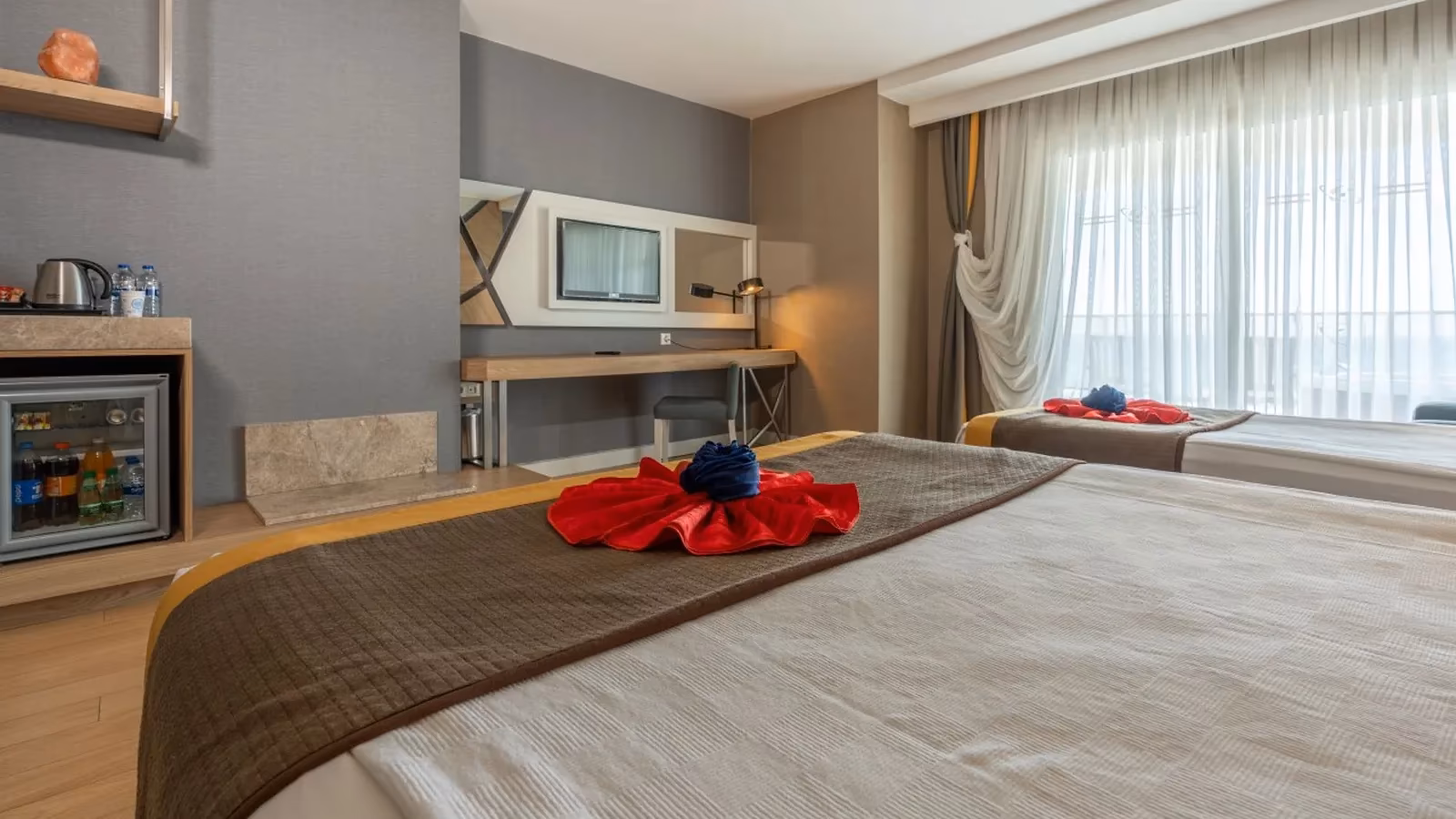 Opgemaakt bed met handdoekdecoratie en een bureau met tv in Saturn Palace Resort