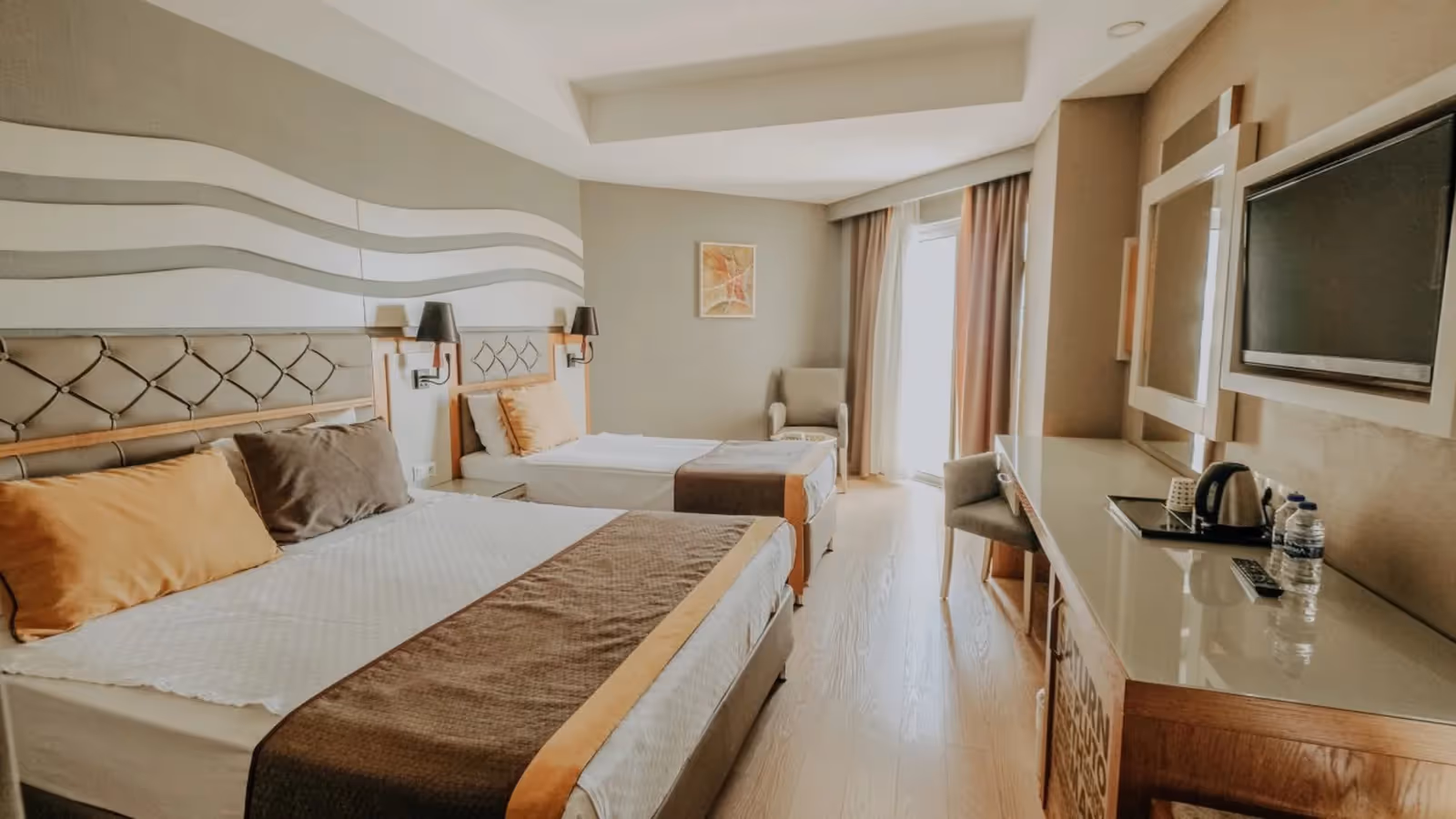 Kamer met een tweepersoonsbed, een eenpersoonsbed en een bureau met waterkoker in Saturn Palace Resort in Lara