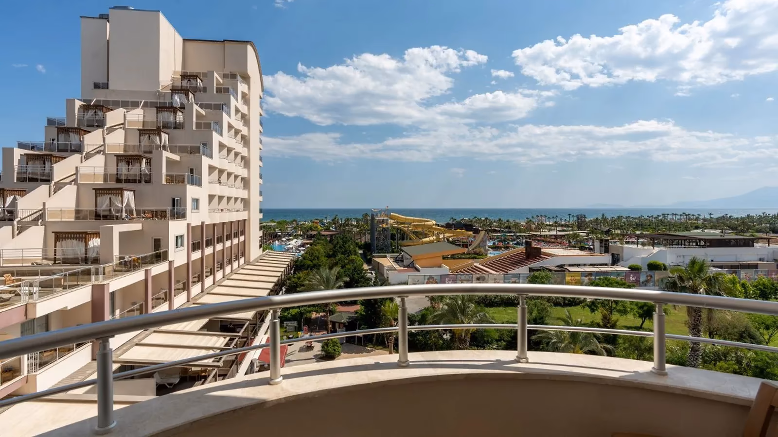 Uitzicht vanaf een balkon van Saturn Palace Resort over de tuin en de glijbanen naar zee, met de hotelvleugel links