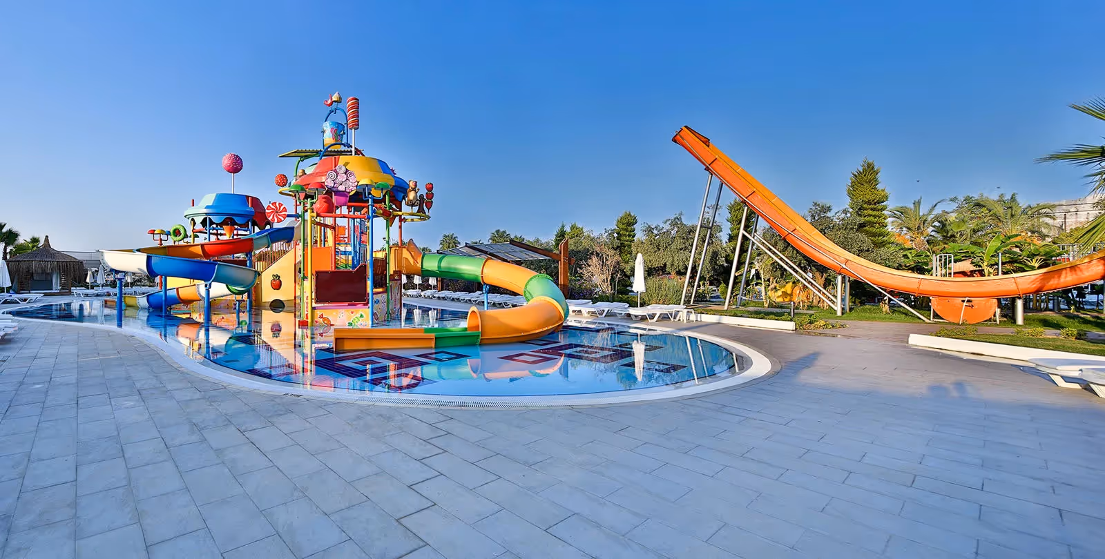 Kinderbad met een kleurrijk speeltoestel met glijbaantjes en een oranje glijbaan erachter bij Saturn Palace Resort in Lara