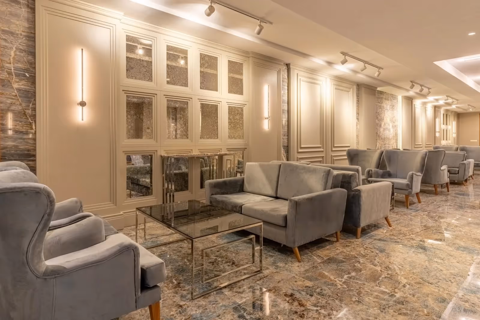 Lounge met grijze fauteuils, glazen salontafels en een marmeren vloer in Saturn Palace Resort in Lara