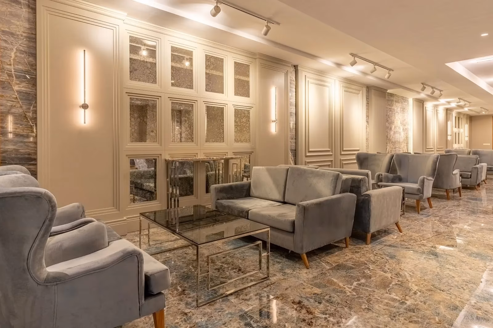 Lounge met grijze fauteuils, glazen salontafels en een marmeren vloer in Saturn Palace Resort