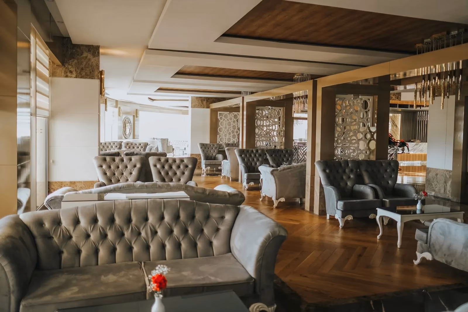 Lounge met grijze chesterfieldbanken en fauteuils bij grote ramen in Saturn Palace Resort