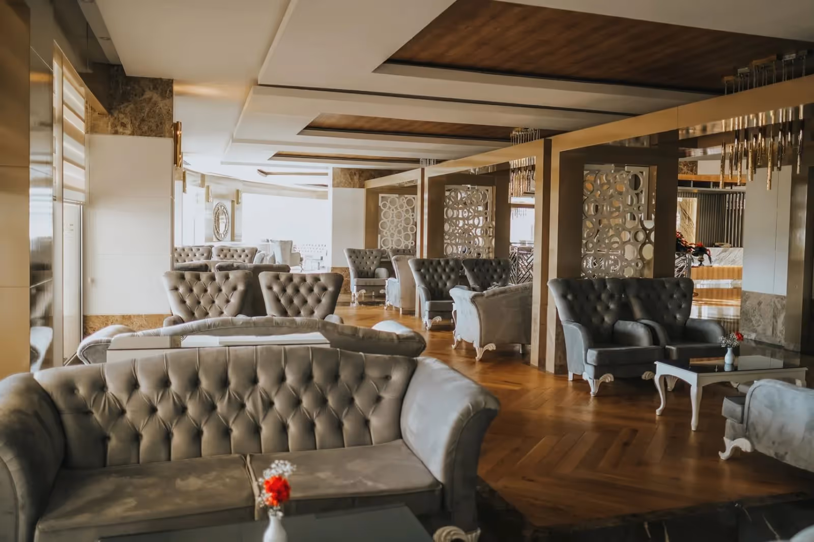 Lounge met grijze chesterfield-banken en fauteuils bij grote ramen in Saturn Palace Resort in Lara