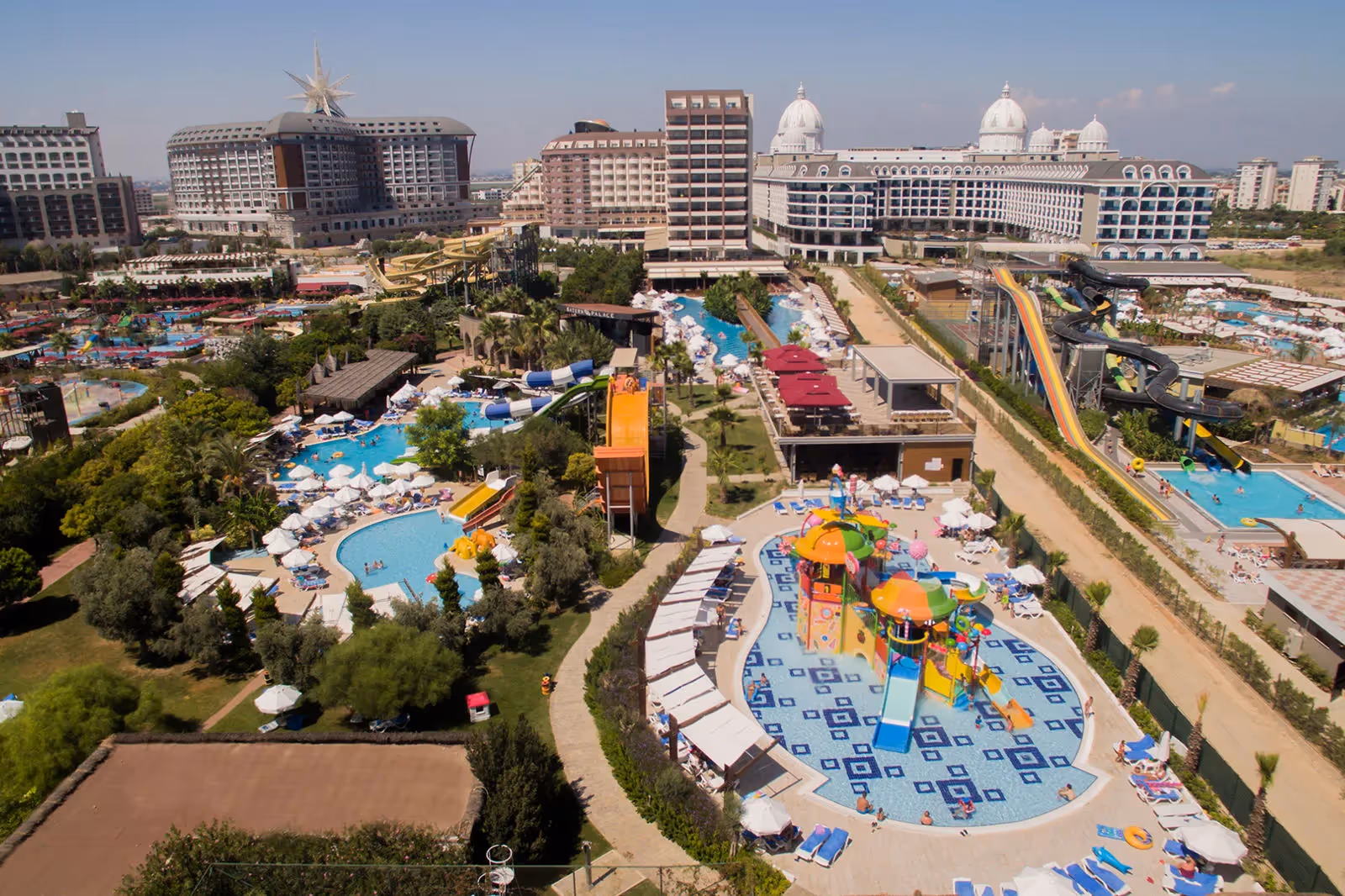 Luchtfoto van het kinderzwembad met speeltoestel, de glijbanen en de hotelgebouwen bij Saturn Palace Resort in Lara, met buurhotels op de achtergrond