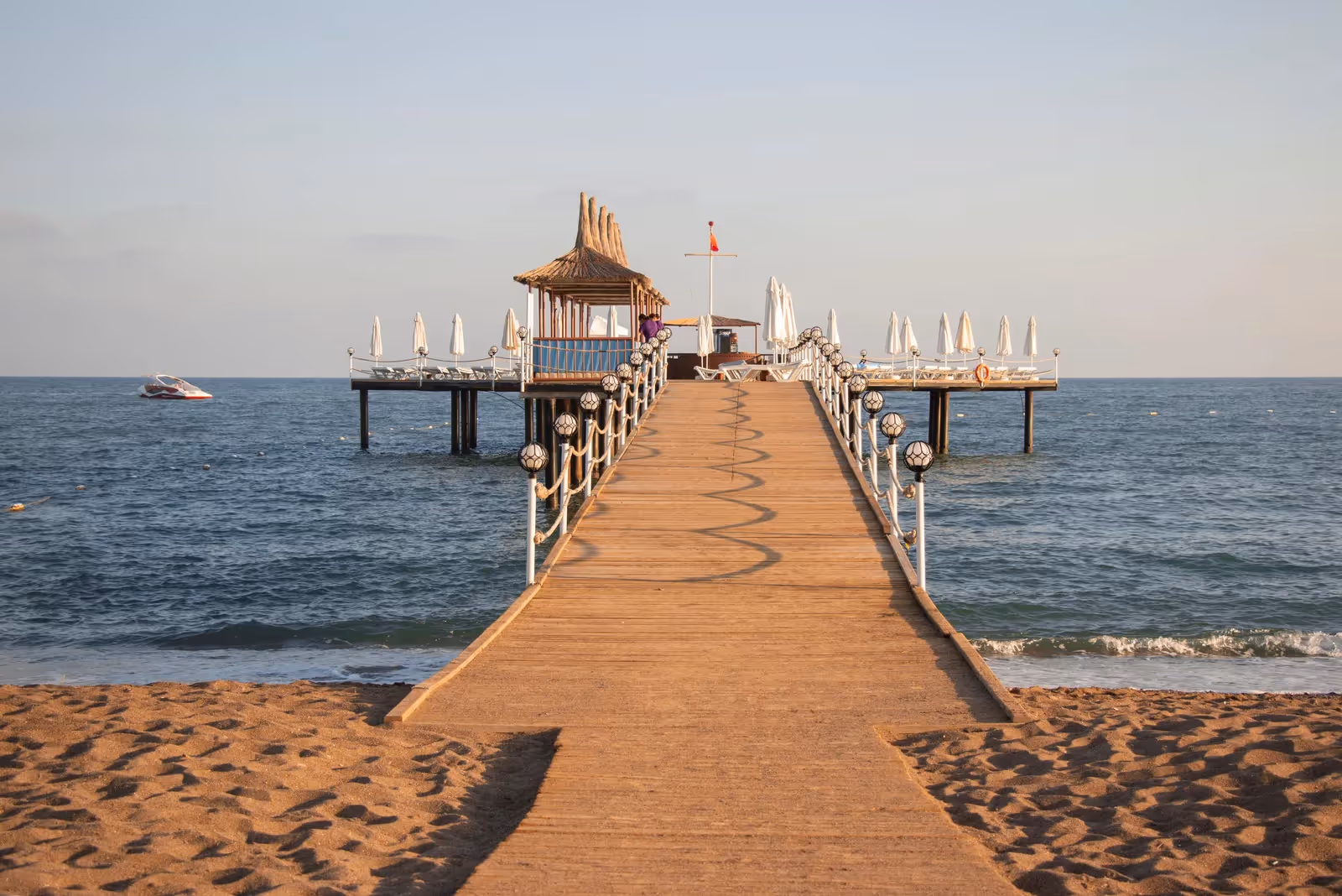 Houten pier met een paviljoen aan het eind, gezien vanaf het zandstrand bij Saturn Palace Resort in Lara