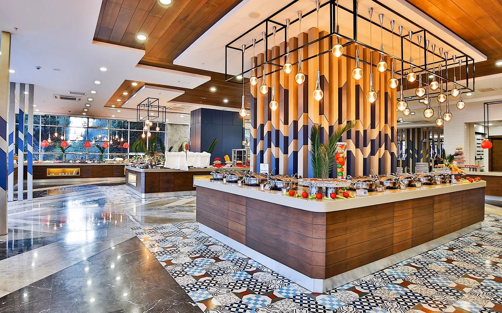 Buffetrestaurant van Saturn Palace Resort met een houten buffeteiland, hanglampen en een tegelvloer met patroon