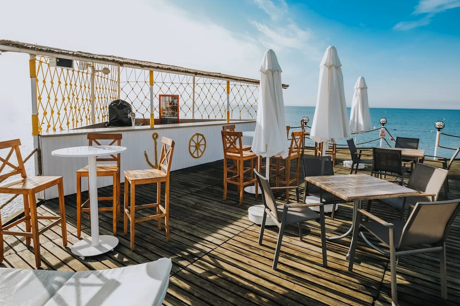 Houten terras aan zee met bartafels, stoelen en parasols bij Saturn Palace Resort